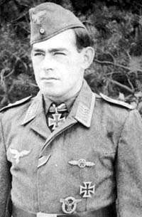 The head and upper body of a young man, shown in semi-profile. He wears a field cap and a military uniform with numerous military decorations including an Iron Cross displayed at the front of his shirt collar. His hair is dark and short, his nose is long and straight, and his facial expression is a determined and confident smile; his eyes gaze into the distance.
