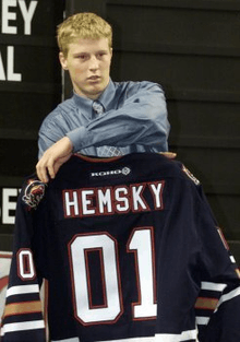 A Caucasian male shown from the waist up.  He is holding a dark blue hockey jersey with the words Hemsky and the number 01 on the back.