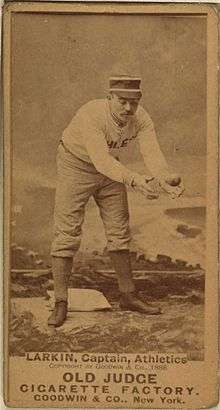 A baseball player is standing, focusing his attention on catching a baseball.