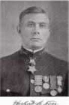 Head of a white man wearing military uniform with many metals adorning it.