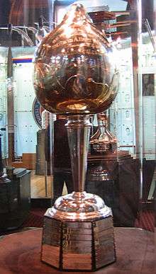 A tall trophy sits inside a glass enclosed display cabinet