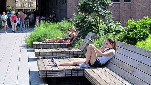 People sitting down on wooden chairs and reading books