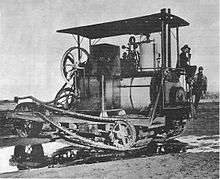 A machine very similar in arrangement to the Holt seventy-five tractor, but with a steam boiler where later models would have the internal combustion engine fitted. A prominent chain drive extends the length of the vehicle from the steam engine to the rear, tracked wheels.