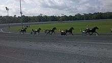 There are six horses racing at Rosecroft Raceway during a qualifying race.