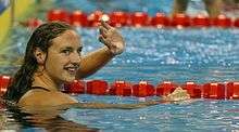  A female swimmer with head above the water, waiving.