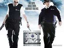 Film poster of two men dressed as British police officers. The man on the left is looking down and is holding a shotgun and a handgun. The man on the right is behind the man on the left with a shotgun and toothpick in his mouth and a explosion behind them. Poster has the films title and the main stars names.
