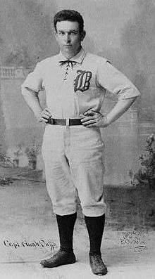 Portrait of a man in a white baseball uniform.