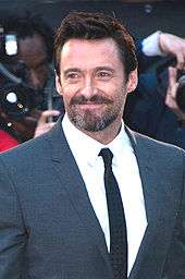 Jackman smiling, wearing a grey suit