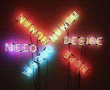Six words are spelled out using neon tube lights. Each word is spelled in a different color of light; the words are roughly laid out like six spokes of a wheel. The six words are NEED, HUMAN, HUMAN, DESIRE, HOPE, and DREAM.