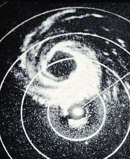 Monochrome radar image of a hurricane. Rain, which the radar detects, is shown as white regions. Concentric circles denote distances from the radar site, located slightly offset from the center of the image.