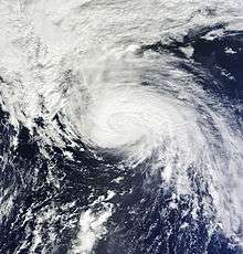 Satellite image of an organized with a ragged eye and some spread out mass of clouds.