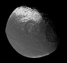 A walnut shaped body illuminated from the bottom-left. The terminator runs from the top to right along the top-right limb. An equatorial ridge runs from the left to right and is convex in the direction of the bottom-left. Above and below it there are dark areas. Above the upper dark area and below the lower one there are bright poles. There numerous craters. Three among them are very large: one sits on the limb at the right another is in the center above the ridge. The third is below the ridge near the left limb.