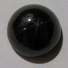 A round cabochon of very dark red garnet which displays a six pointed star effect under intense lighting.