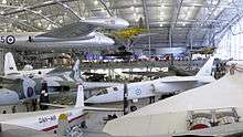 Various aircraft, large and small, exhibited in a hangar.