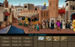 A video game screenshot showing the two protagonists in the middle of a crowded marketplace. The lower part of the image shows a variety of objects on the right side and a number of verbs such as "Pick up", "Use" and "Talk to" on the left side. The mouse cursor is pointing at Sophia, making the current command "Talk to Sophia".