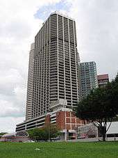 Ground-level view of 50-storey box-like building with dark, receded windows and cut-off, diagonal corners