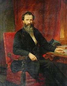 Portrait of bearded man (Isaac Holden) sat at a desk