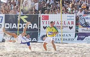 Photograph of two men in a beach soccer pitch