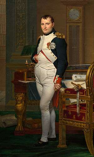 Portrait of Napoleon in his forties, in high-ranking white and dark blue military dress uniform. In the original image He stands amid rich 18th-century furniture laden with papers, and gazes at the viewer. His hair is Brutus style, cropped close but with a short fringe in front, and his right hand is tucked in his waistcoat.