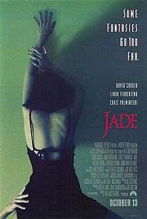 A woman in an open back black dress, arm outstretched above her head, she is leaning against a green wall. From below another hand holds her at the waist. The top right of the poster features the tagline "Some fantasies go too far."