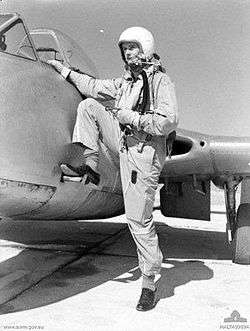 Man in flying suit and helmet climbing on to Vampire jet