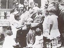 Riley seated in a chair surrounded by children