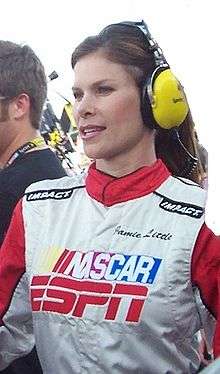 Dressed in a NASCAR/ESPN race reporter uniform, wearing a headset