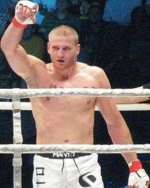 Jan Błachowicz in the ring celebrating vitory with his right hand in the air.