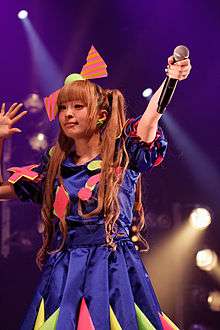 A woman with brightly coloured clothing and a large bow in her hair.