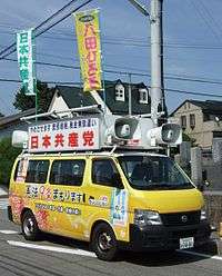Small yellow van with speakers attached to the top.