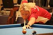 Woman shooting pool while hunched over a table