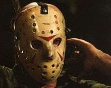 The actor wears a modified goalie mask. Three red triangles have been painted on the mask.