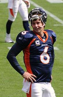 A football player in a blue-and-orange uniform stands on the field.