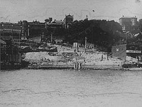 Photograph shows construction on the foreshores of Kirribilli above Jeffrey Street circa 1930. St. Aloysius College incorporating Dr. Cox's home and the tower of Star of the Sea Church are visible on the skyline. The homes Greencliffe and Craiglea are also visible on the right hand side above M. Steel boatshed
