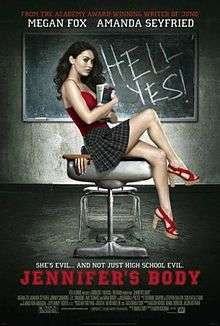 Jennifer holding books in her arms sitting on a school desk, wearing a red top and short plaid skirt, in front of a blackboard with the words HELL YES! written in chalk. A hand can be seen trapped by the lid of the schooldesk. The poster bears the tagline "She's evil... and not just high school evil" in white block capitals, with the film title underneath in large red block capitals.