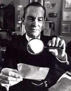 A man in a suit peers at a piece of paper through a magnifying glass.
