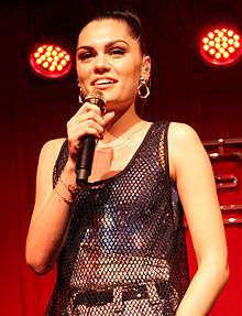 Jessie J is holding a golden microphone while performing.