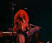 Jethro Tull leader Ian Anderson, wearing a codpiece and tights, stands on one leg as he plays a soprano saxophone