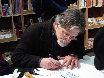 Photo of a bearded and bespectacled man drawing