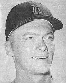 A smiling young man wearing a baseball cap with an Old English "D" on the front looks to the right of the image.