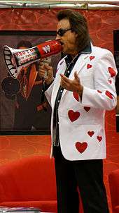 Jimmy Hart, holding a megaphone and wearing a white jacket with red stars on it