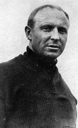 Head and shoulders of a middle-aged man, with receding hairline, in a dark turtleneck sweater.