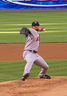 A man throwing a pitch with his left hand and one foot lifted off the ground