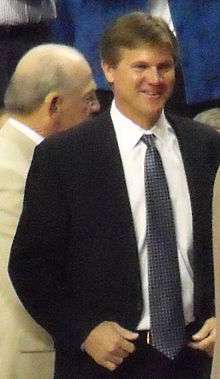 A smiling man in his forties standing and wearing a suit