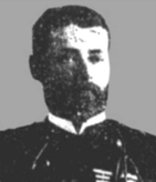 Head of a man with full beard wearing a dark military jacket over a white shirt.