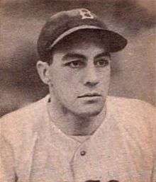 A man in a white baseball jersey and a dark cap with a white "B" on the center looks to the right.