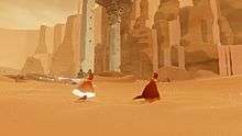 A red-robed figure runs through the sand in front of some stone ruins, accompanies by another figure. The trailing figure's robe and scarf are glowing.
