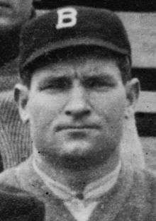 A close-up of a man wearing a dark baseball cap with a white "B" on the center.