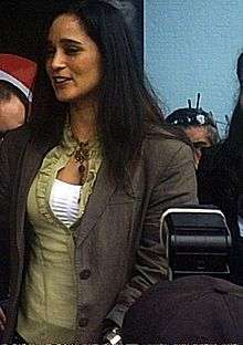 A woman with straight hair wearing a green blouse.