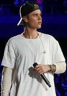 Justin Bieber performing in white outfit on tour.